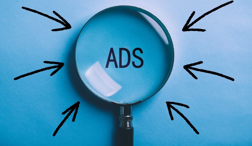 Magnifying glass zooming in on the word "ADS" with a blue background and arrows pointing towards it, symbolizing focus on Responsive Search Ads.