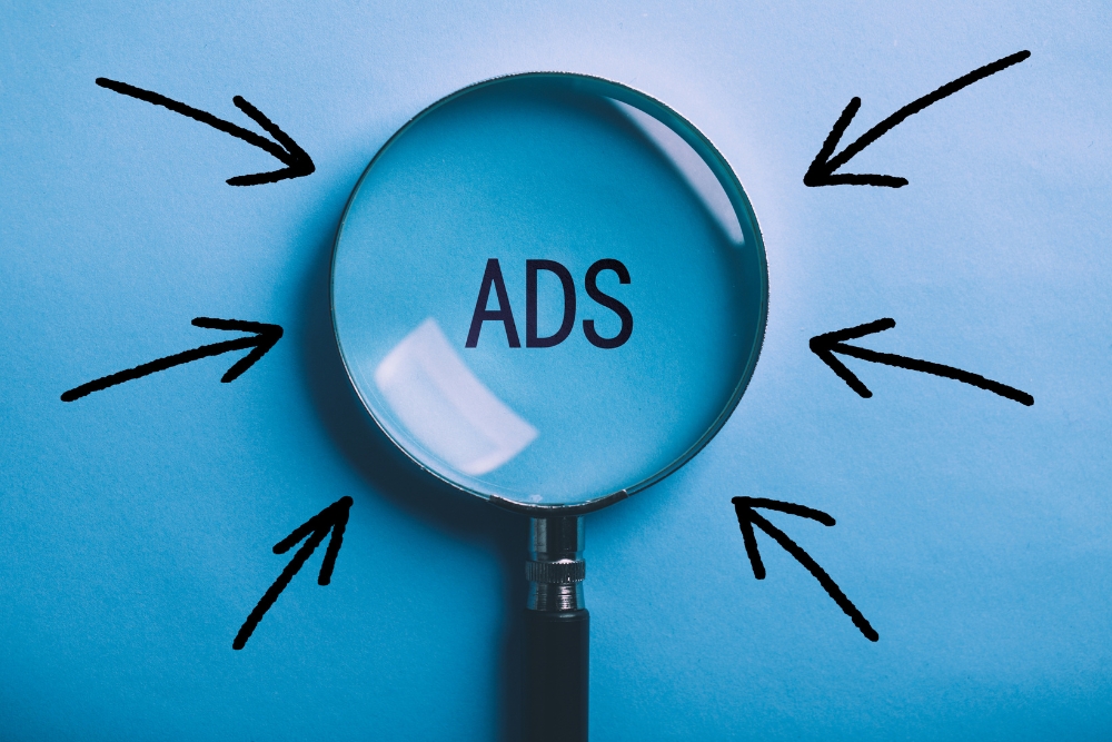 Magnifying glass zooming in on the word "ADS" with a blue background and arrows pointing towards it, symbolizing focus on Responsive Search Ads.