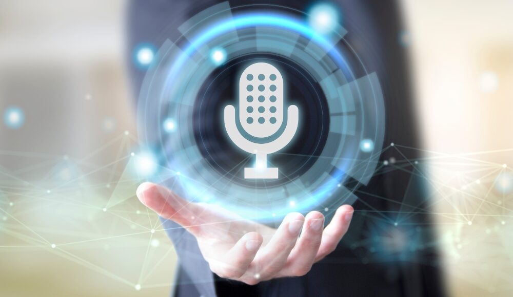 A man in a suit holds a holographic image of a microphone, symbolizing voice search optimisation. The background is composed of abstract, digital network elements, emphasizing technological advancement in voice search technology.