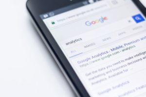 A phone displaying a Google search result for "analytics," emphasising the relevance of Google Ads for mobile optimisation. 