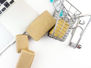 Mini shopping cart with packages near a laptop, representing ecommerce checkout and live chat for ecommerce website.