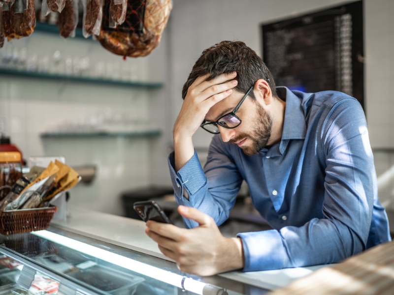 Frustrated man looking at smartphone in a store, wondering why Google Ads are not showing up.