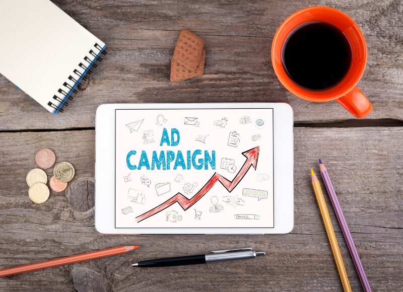 Tablet showing "AD CAMPAIGN" with upward arrow, suggesting ways to improve campaign performance.