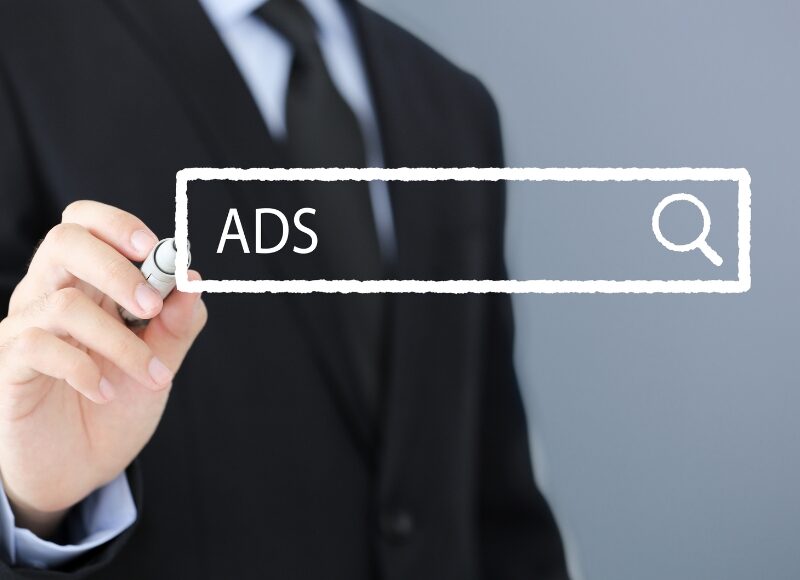 A business professional writing "ADS" in a digital search bar, representing continuous improvement in Google Ads optimisation.