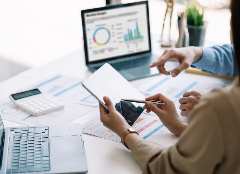 Google Ads professionals collaborating using tablet and data dashboards to lower CPC effectively