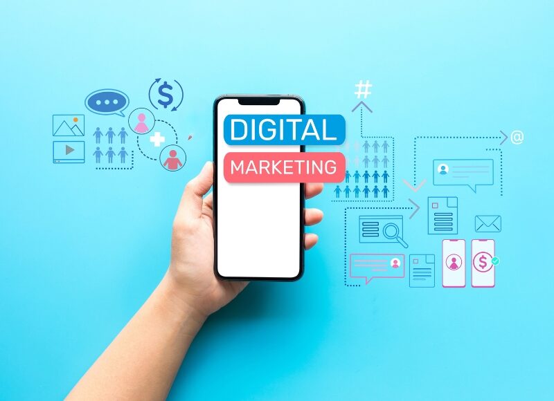 A hand holding a phone with digital marketing icons around it, showcasing tools used in online marketing for builders.