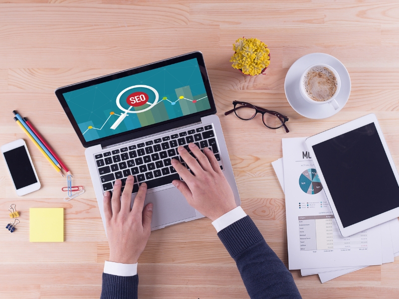 Google Search Engine Consultants analyzing SEO growth on laptop with charts, reports, and digital marketing tools.