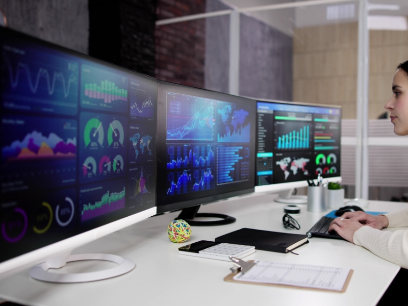 google advertising help showing competitor insights on multiple data dashboards across three monitors