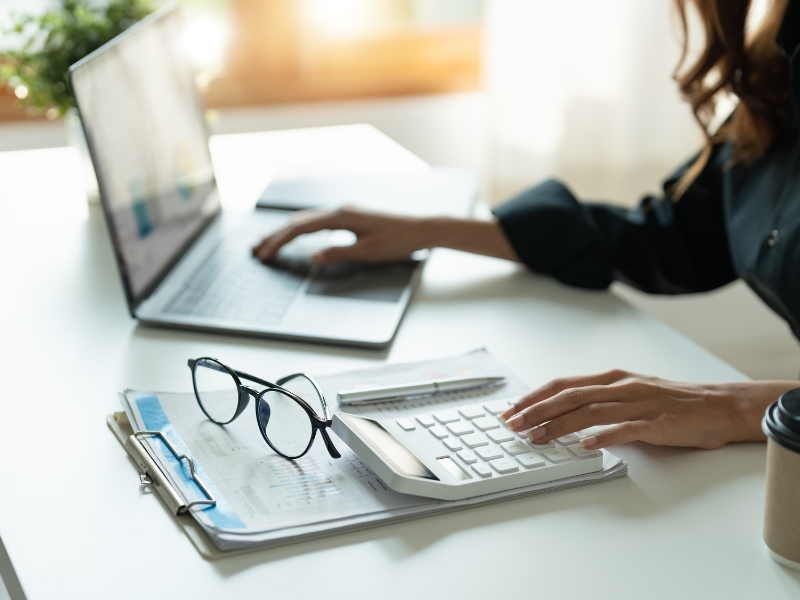 Professional analysing reports and budget on laptop and calculator for Google Ads Management performance tracking.