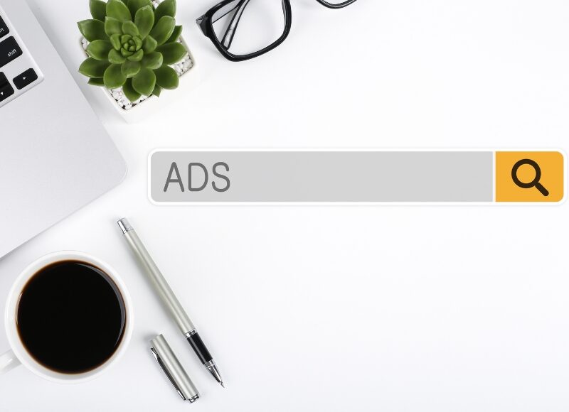 Hands typing on laptop managing social engagement and conversions in a google ads campaign