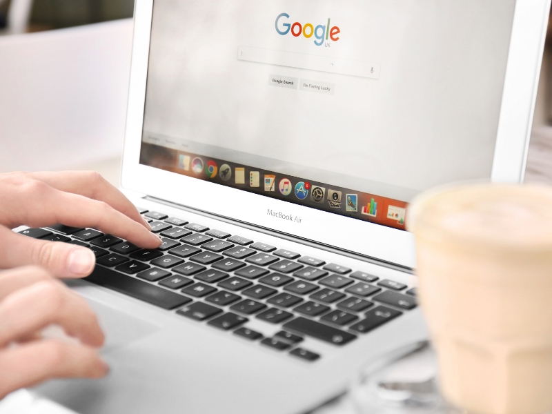 Person using a laptop with Google search open, showing a google ads specialist working online.