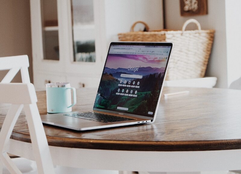 Laptop on wooden table displaying Google homepage for Google Ads Reporting insights.