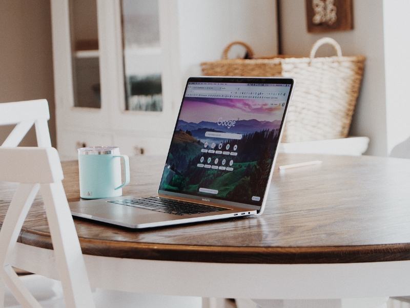 Laptop on wooden table displaying Google homepage for Google Ads Reporting insights.