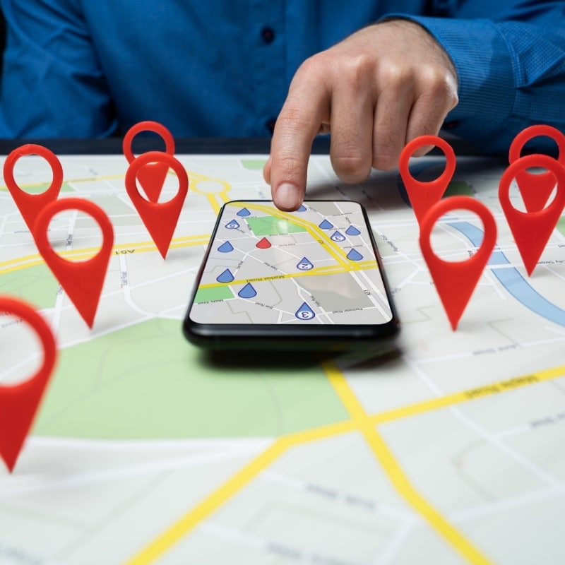 Local SEO strategy showing a smartphone map with red location pins and a finger selecting a business location