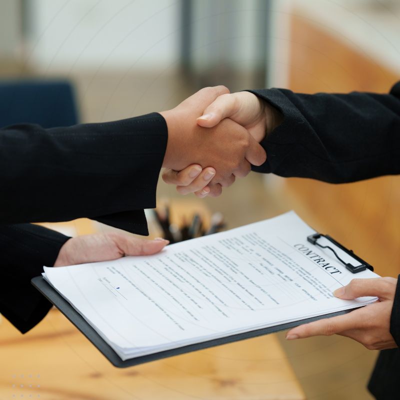 A professional handshake over a contract, symbolising a successful partnership in digital marketing for insurance agents.