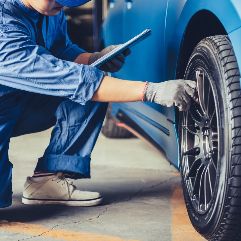 Technician inspecting car tire in a workshop, highlighting digital marketing for automotive industry services for customer engagement and growth.