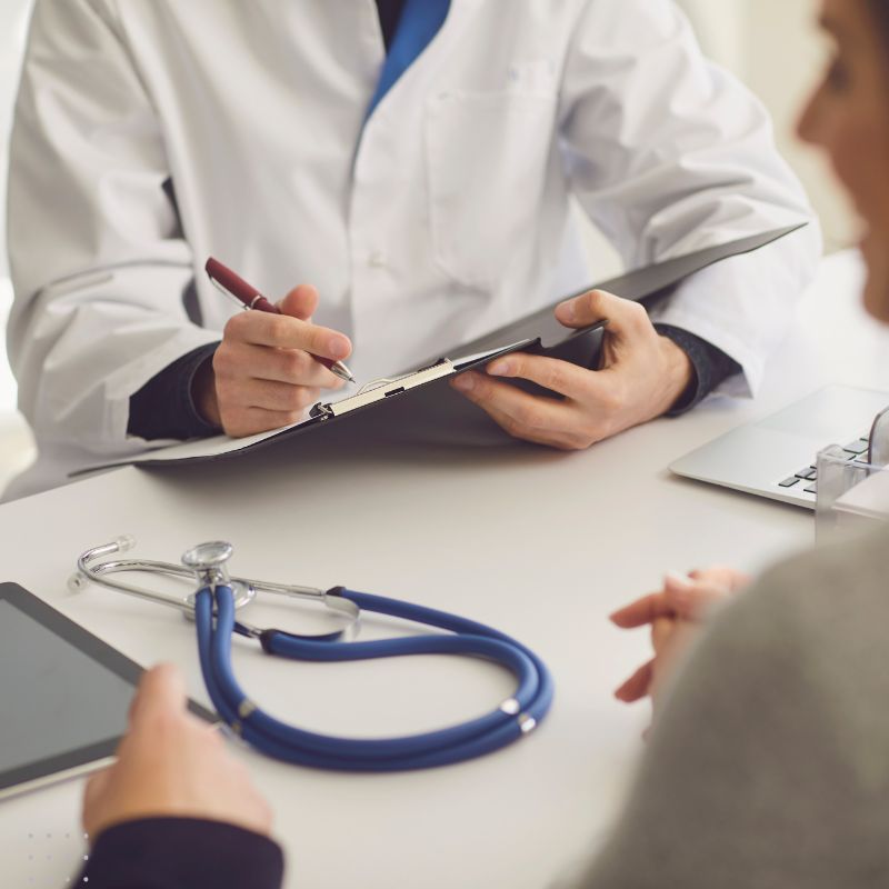 A doctor’s office scene featuring a patient consulting with a doctor holding a clipboard, highlighting the importance of digital marketing strategies for medical practices.