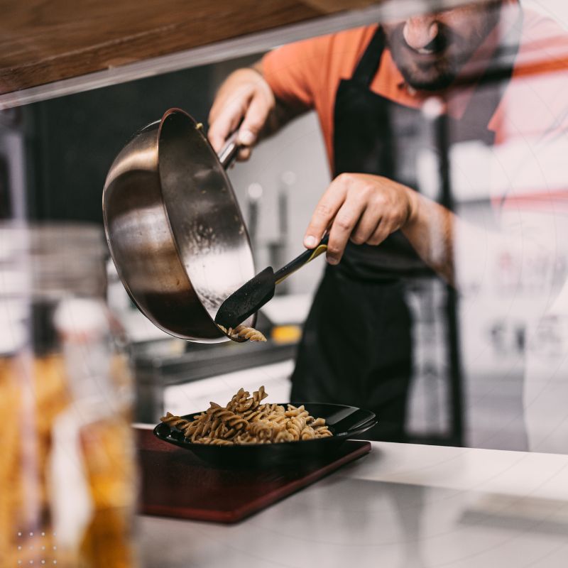Chef cooking in a pan with a blue and white triangle layout, symbolising the fusion of culinary arts and digital marketing for the food industry.