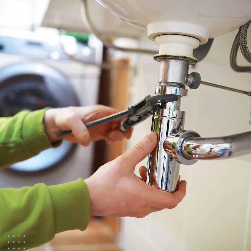 Digital Marketing for Plumbing Businesses - Close-up of hands using wrench on chrome plumbing fixture under sink, symbolising repair services.