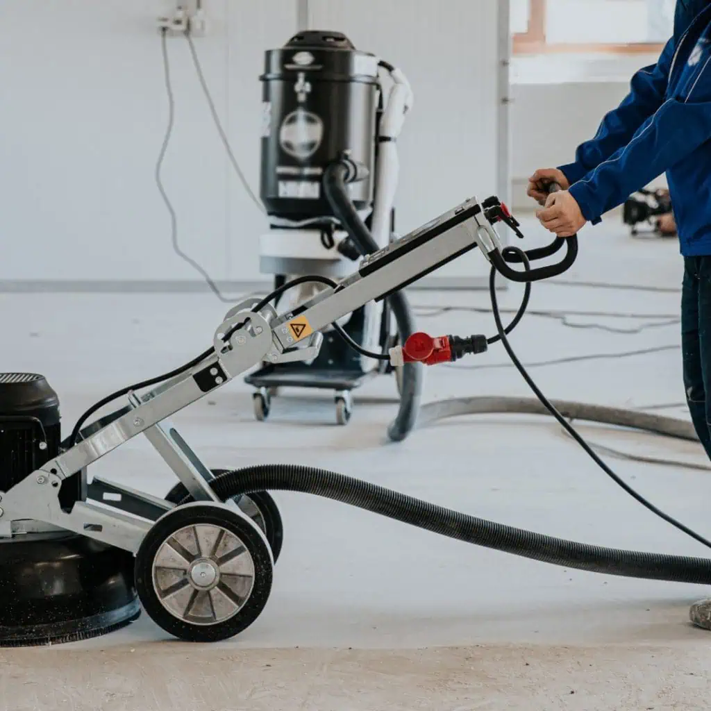 Worker operating a floor grinder during epoxy flooring preparation