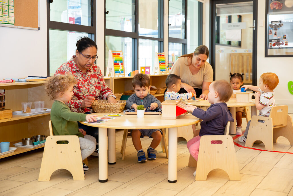 Educators and young children engaged in activities inside a Montessori classroom