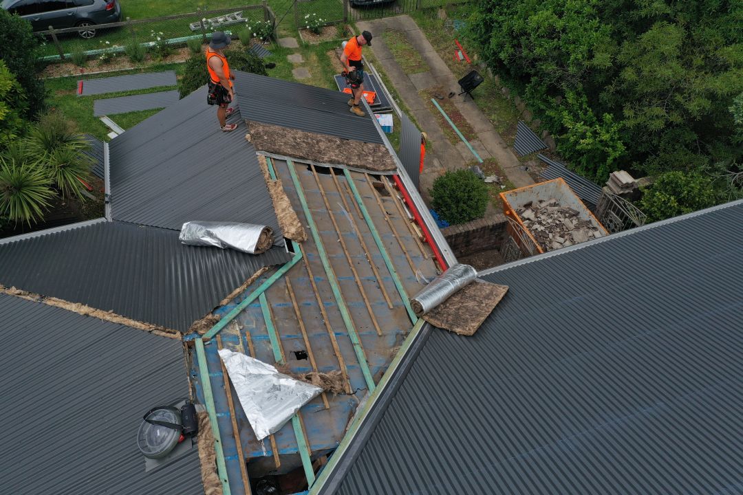 Roofers installing metal roofing sheets on a residential property in NSW